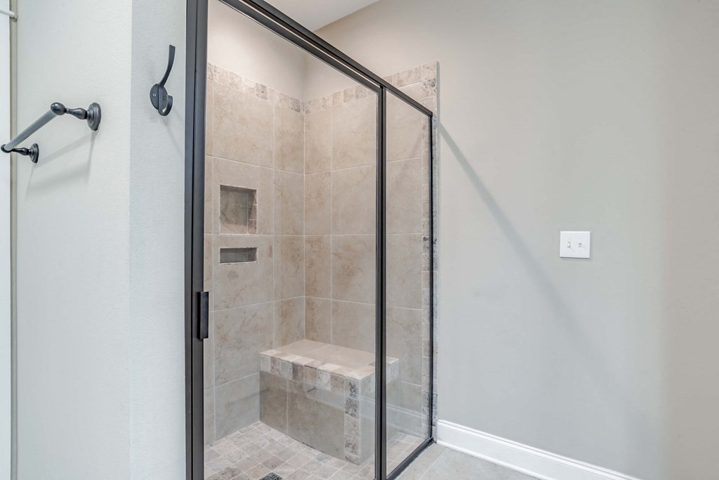 A bathroom with a walk-in shower and a glass door.