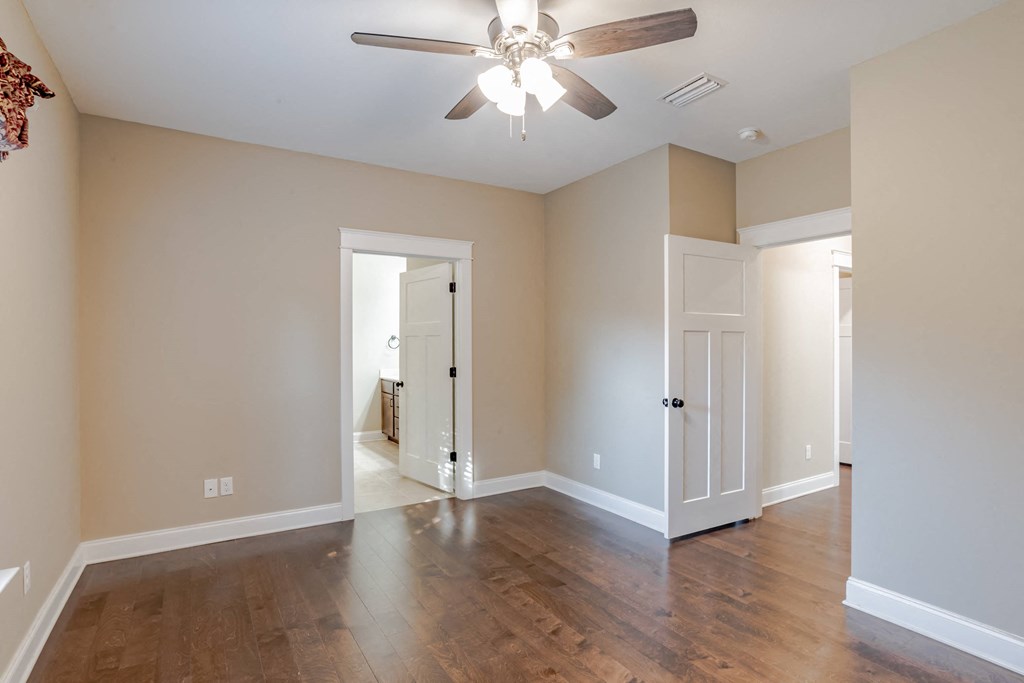 A room with a ceiling fan and wooden floors.