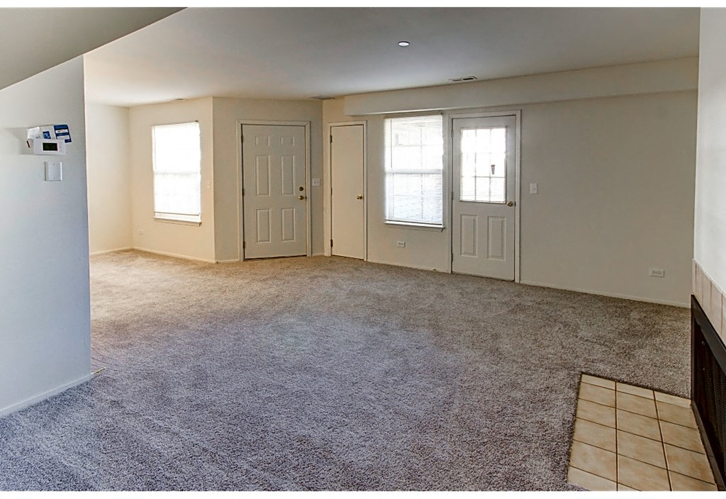 an empty living room with carpet and two doors