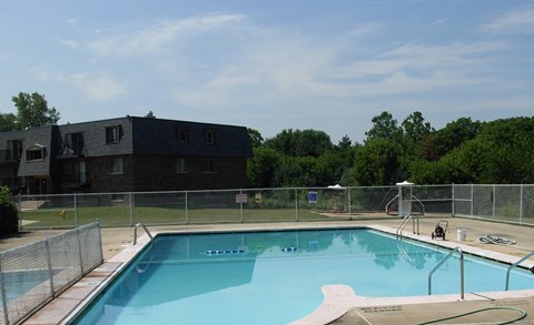 A swimming pool with a fence around it and a building in the background.