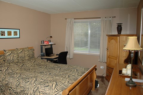 A bedroom with a bed, desk, and chair.