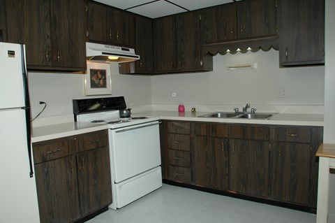 A kitchen with dark wood cabinets and white appliances.