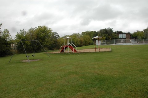 A playground with a swing set and a seesaw.