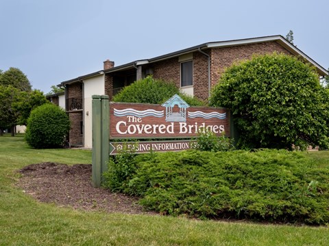 A sign for "The Covered Bridges" stands in front of a house.