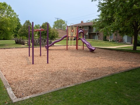 A playground with a purple slide and a purple swing set.