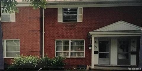 A red brick house with a white door and windows.