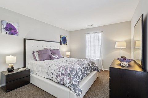 A bedroom with a large bed and a nightstand with a lamp.
