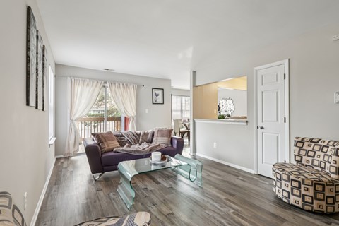 A living room with a purple couch and a glass coffee table.