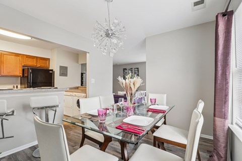 A dining room with a glass table and white chairs.