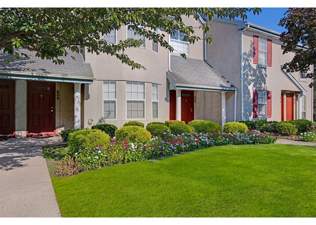 a home with a green lawn and flowers in front of it