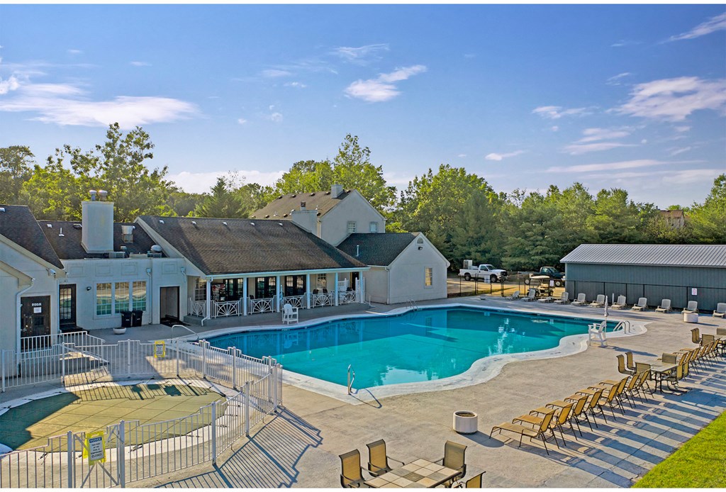 a swimming pool with chairs around it in front of a building