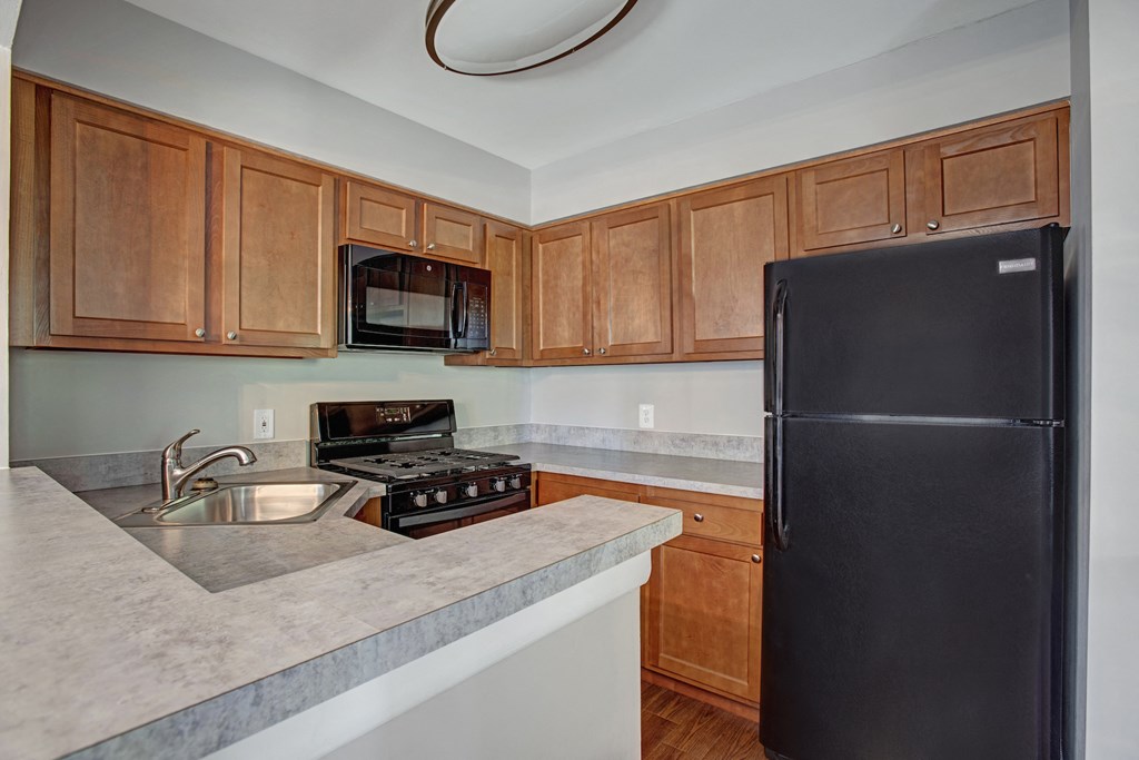 an updated kitchen with black appliances and wooden cabinets