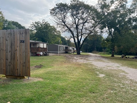 a dirt road with a wooden fence in front of a campsite