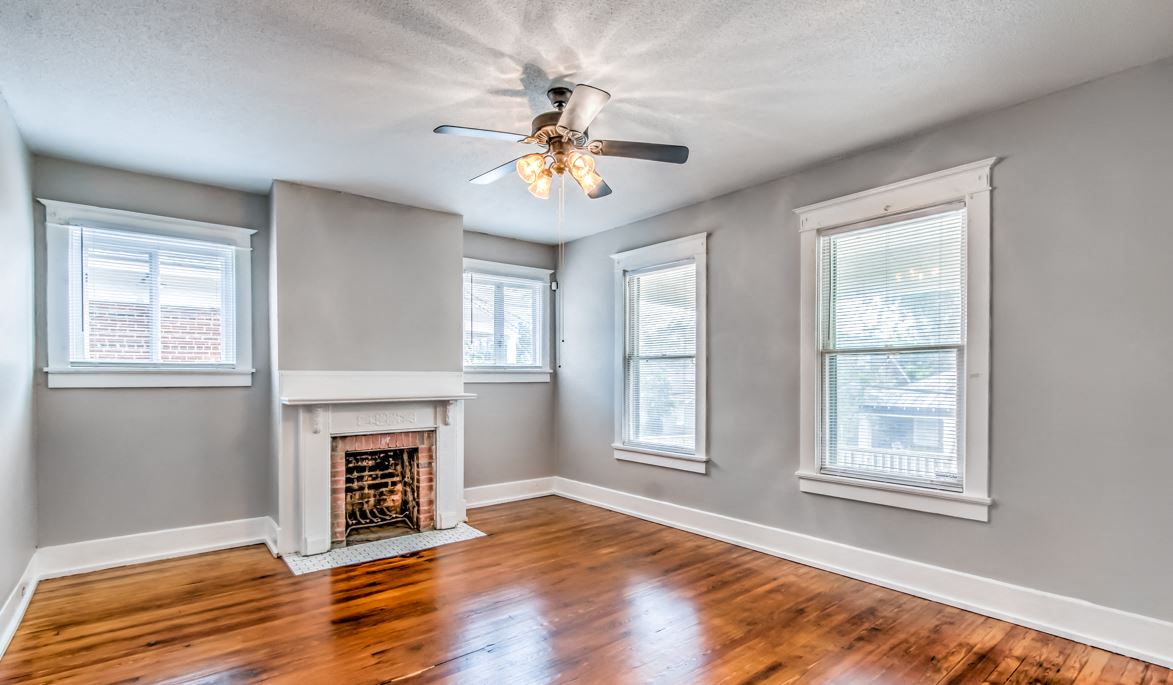 an empty living room with a fireplace and a ceiling fan