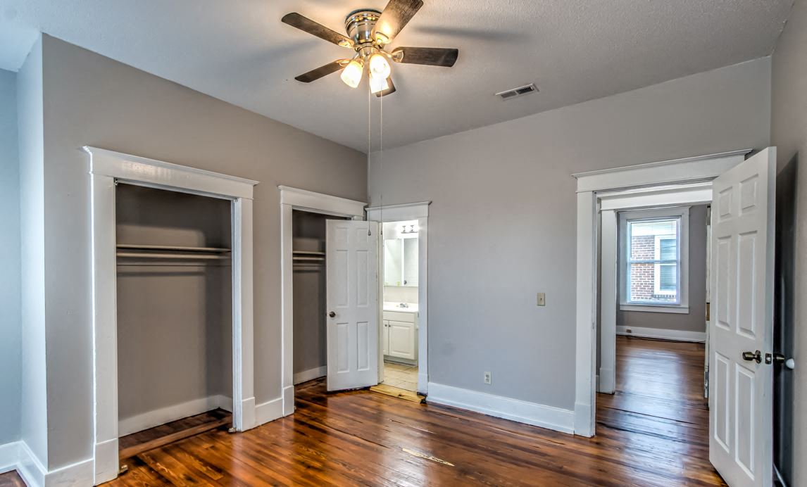 an empty living room with wooden floors and a ceiling fan