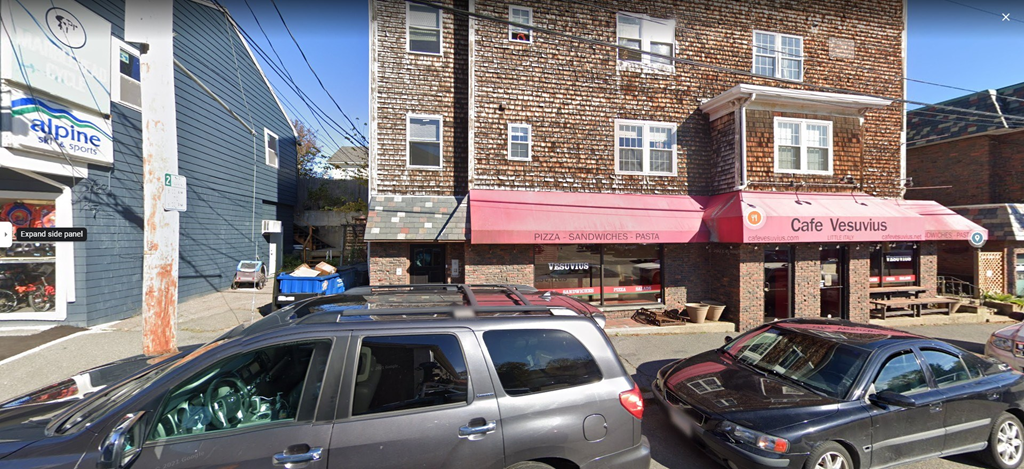 a city street with cars parked in front of a brick building