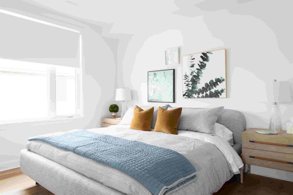a bedroom with white walls and a bed with a blue blanket and pillows