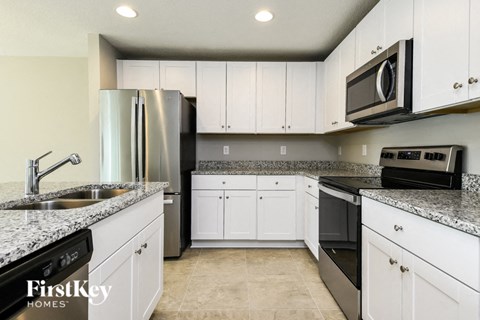 A kitchen with white cabinets and a granite countertop.
