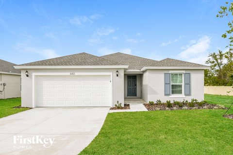 a white house with a garage door and a lawn