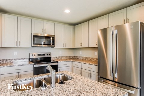 A kitchen with a stainless steel refrigerator and a granite countertop.