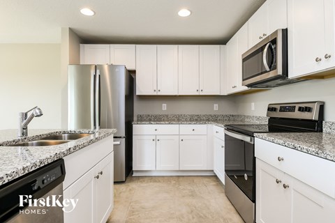 a kitchen with white cabinets and stainless steel appliances and granite counter tops