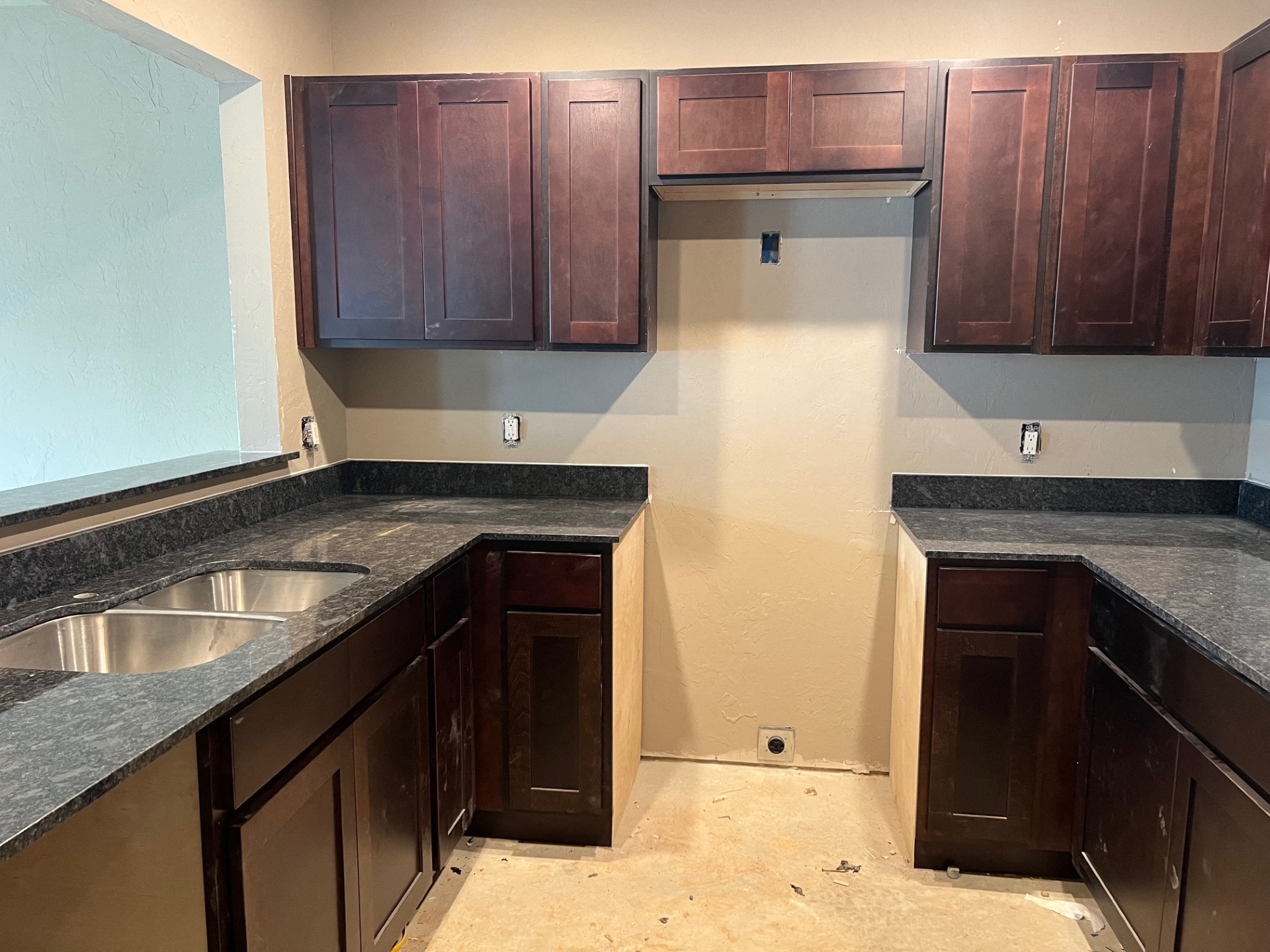 an empty kitchen with dark wood cabinets and a sink