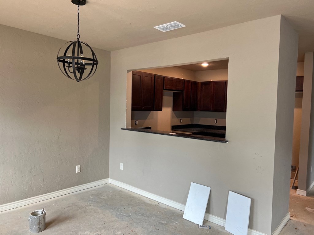 a dining room with a window into the kitchen and a chandelier