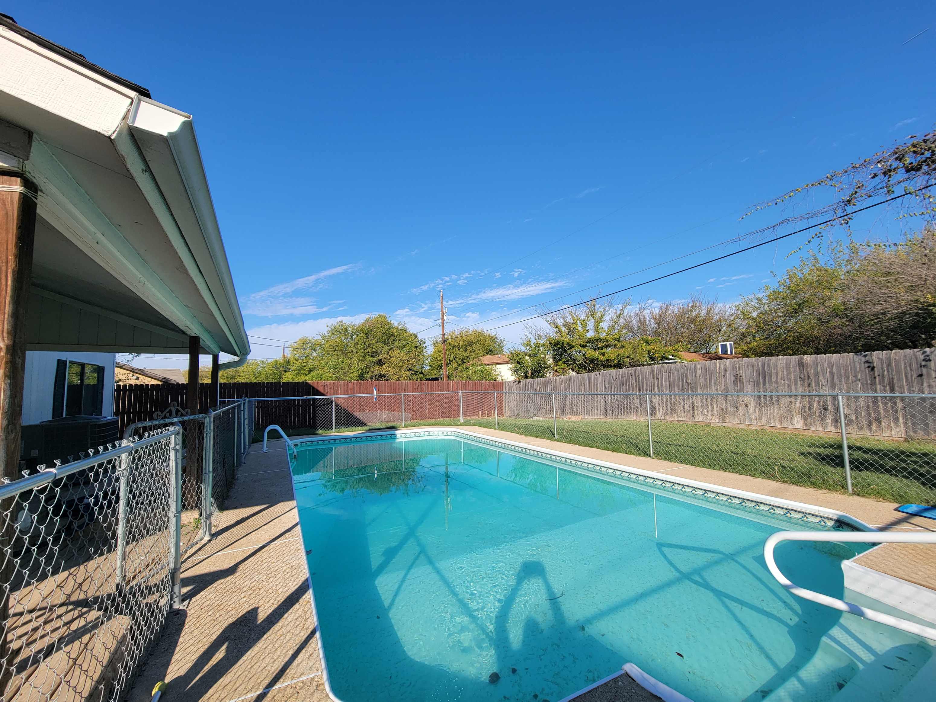 the pool is next to the house and has a fence around it