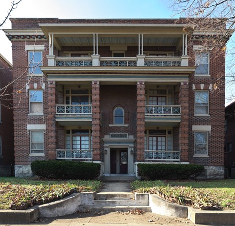 A two-story brick building with a balcony on the second floor.