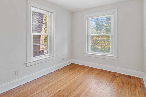 A room with two windows and wooden flooring.