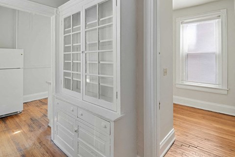 A white kitchen with a wooden floor and a white fridge.