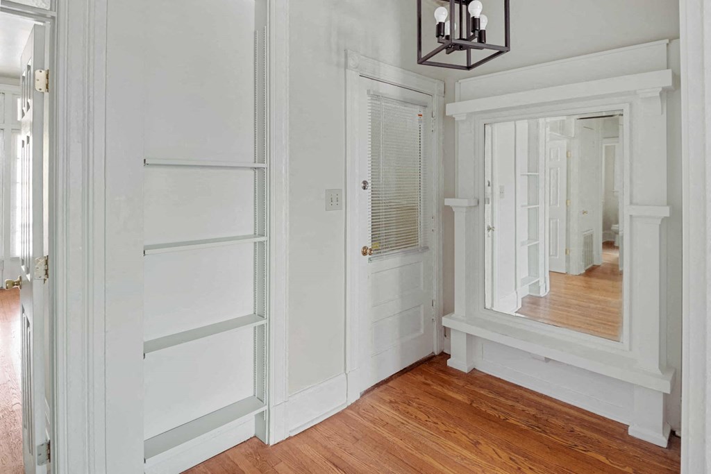 A white hallway with a mirror and a light fixture.