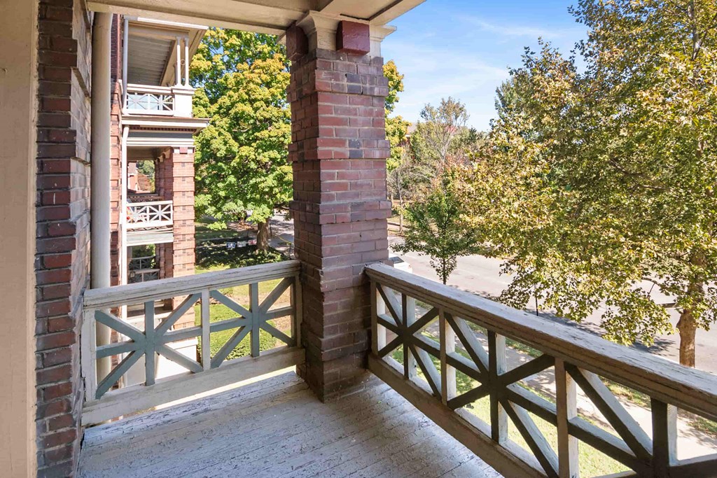 A balcony with a brick pillar and a wooden railing.