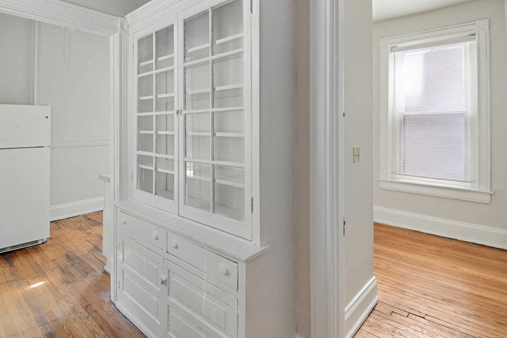 A white kitchen with a wooden floor and a white fridge.