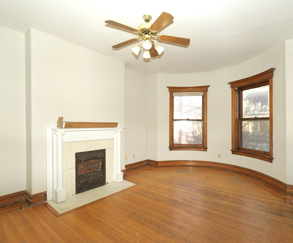A room with a fireplace and a ceiling fan.