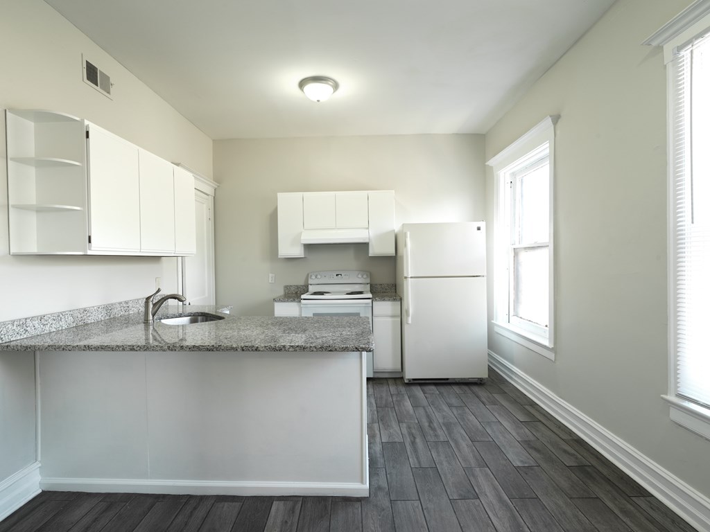 A kitchen with a granite countertop and white cabinets.