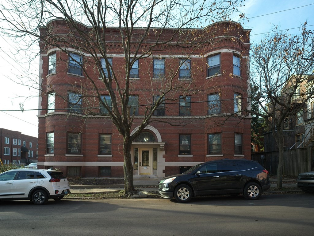 A black car is parked in front of a red brick building.