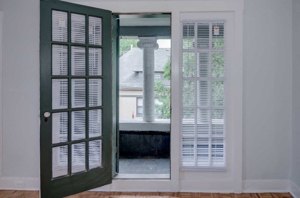 A white door with a green door frame is open to a room with a window.