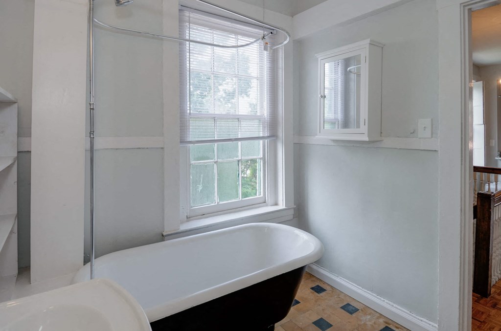 A white bathroom with a tub and a window.