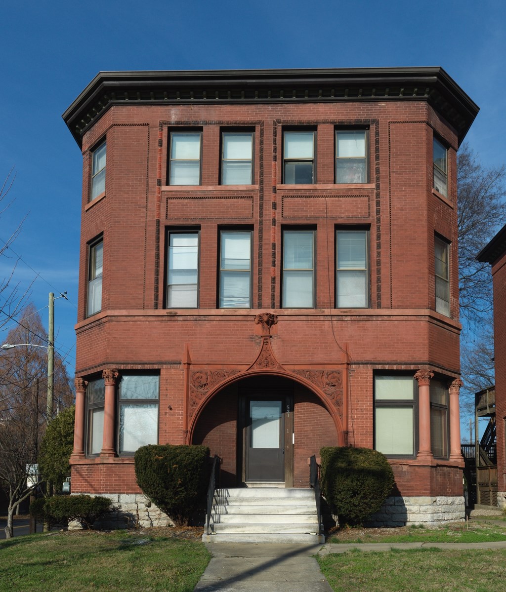 A red brick building with a black roof and a black gate.