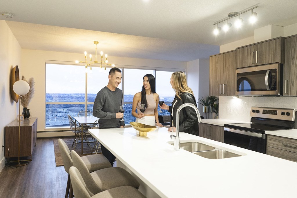 three people standing around a kitchen counter in an apartment