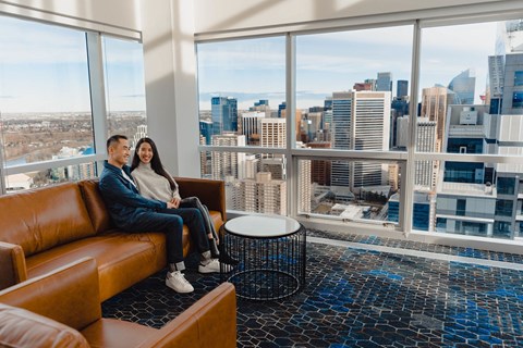 a couple sitting on a couch in a room with a view of the city