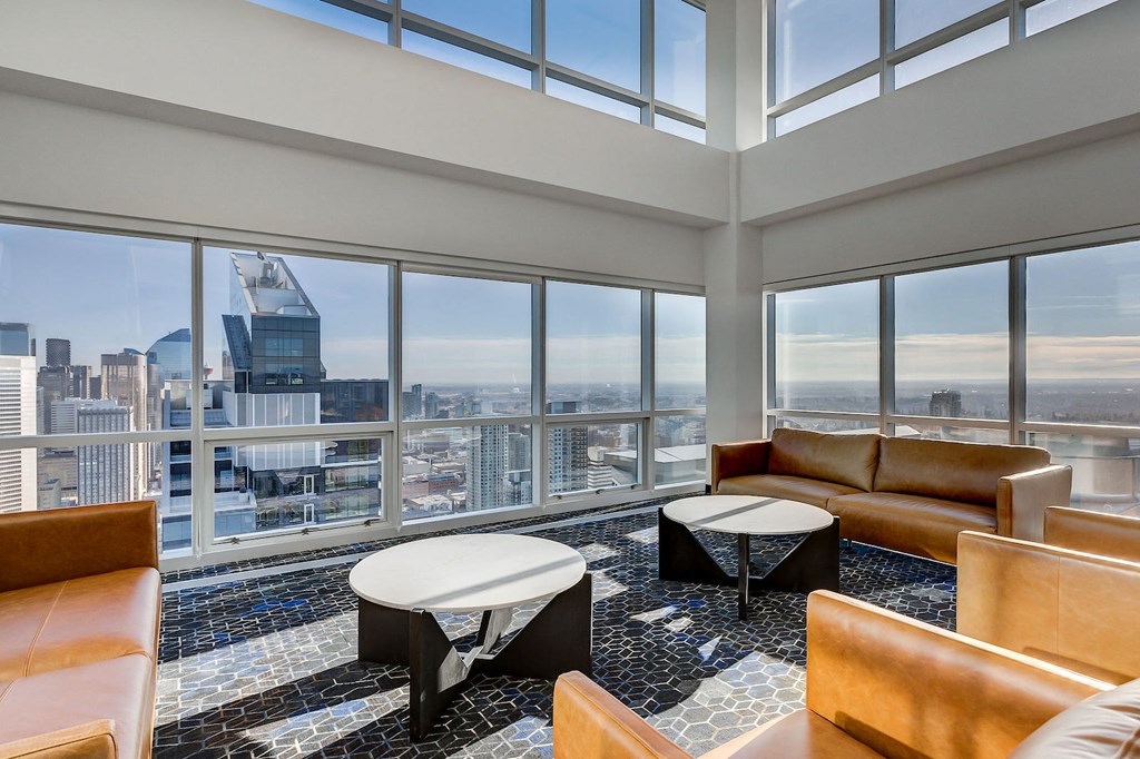 a living room with leather couches and tables and a view of the city