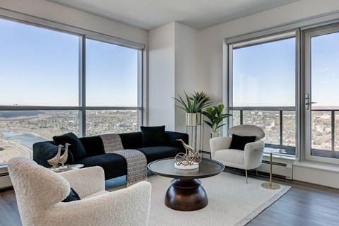 a living room with a view of a city and a couch and chairs