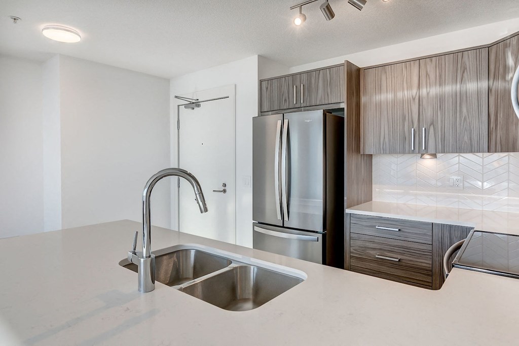 a kitchen with a sink and a stainless steel refrigerator