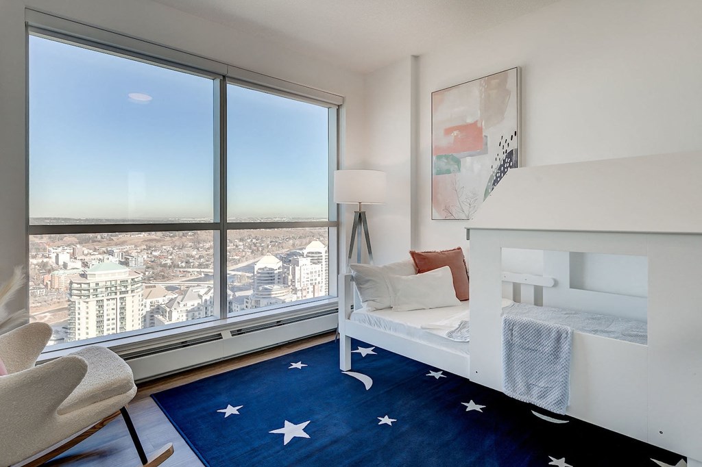 a bedroom with a large window and a bed and a blue rug