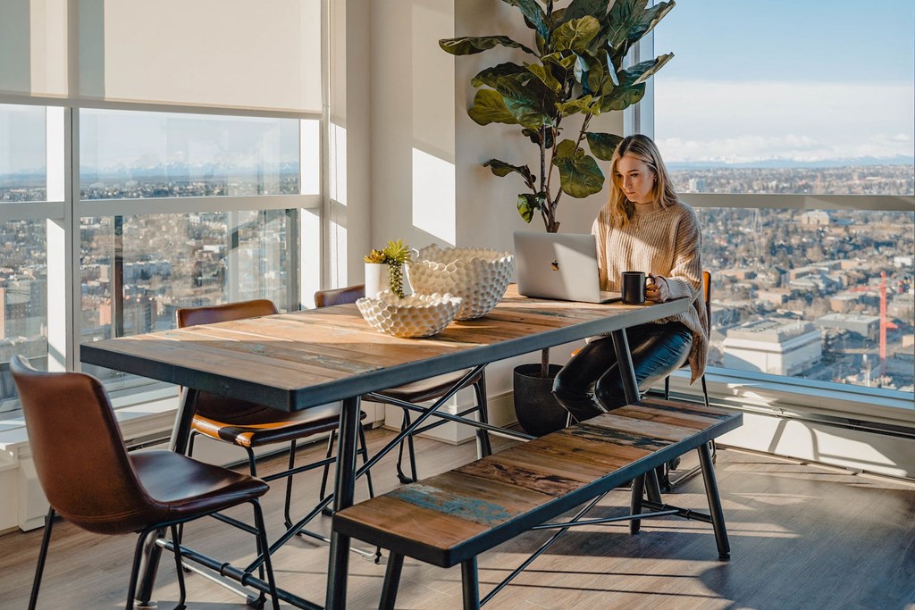 a woman sitting at a table with a laptop in front of a window