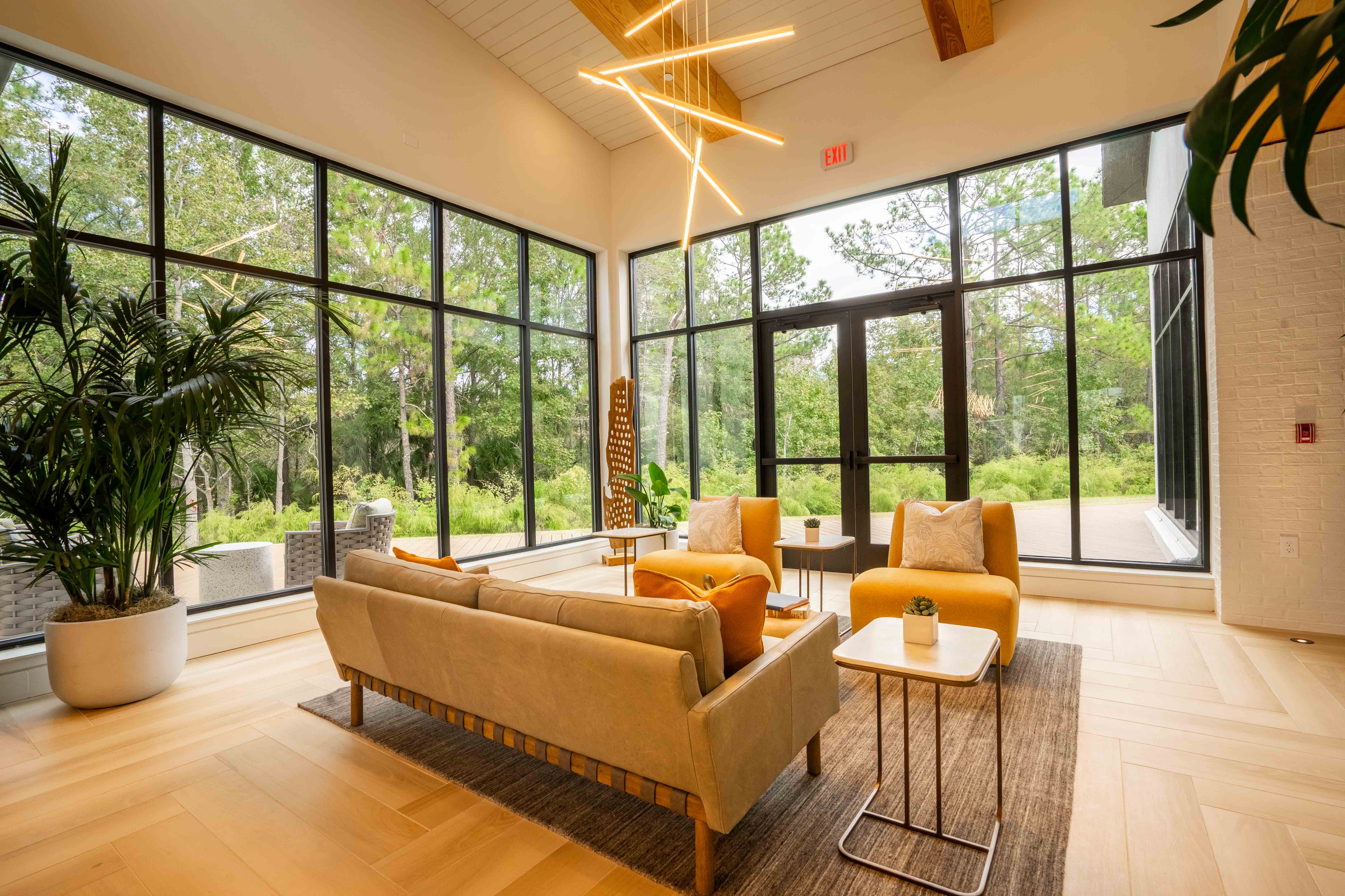 a living room with couches and chairs and large windows
