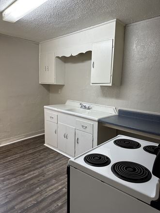 an empty kitchen with white appliances and a stove top oven