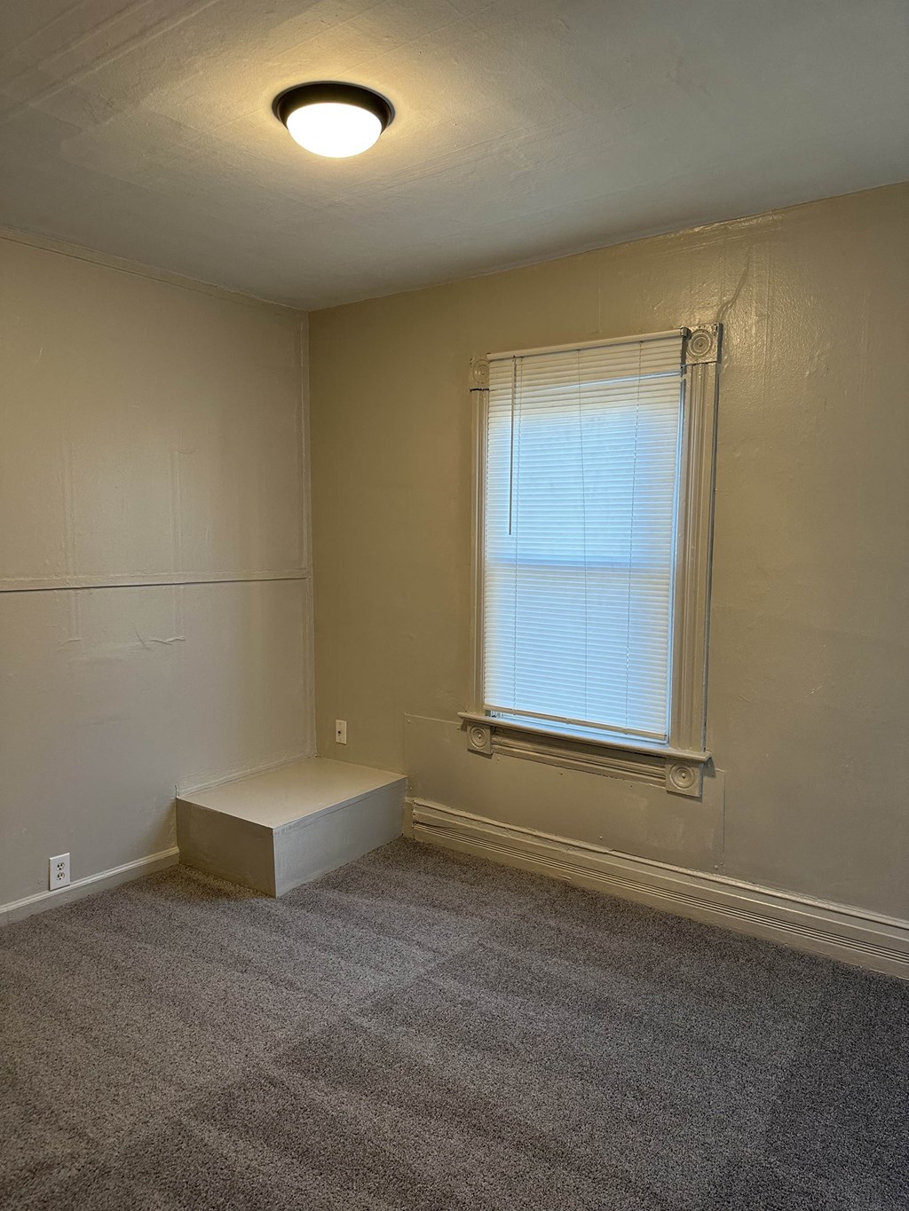 an empty room with a window and a bench